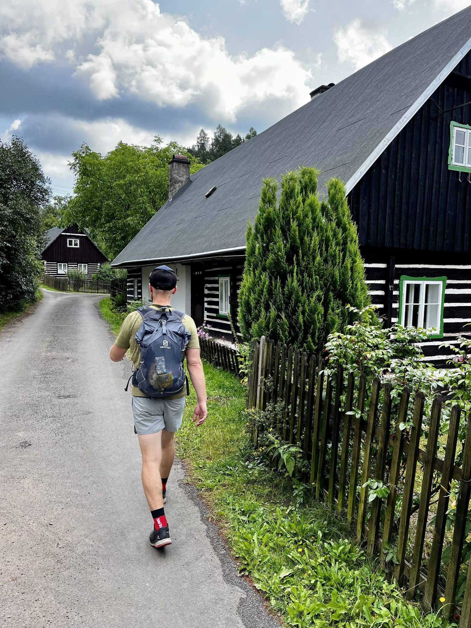 Bežec s batohom na ceste popri drevenici